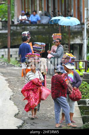 Frauen, die Sarongs verkaufen, die auf ihren Köpfen gebündelt sind, werden in Tegalallang in Ubud, Bali, Indonesien, verkauft Stockfoto