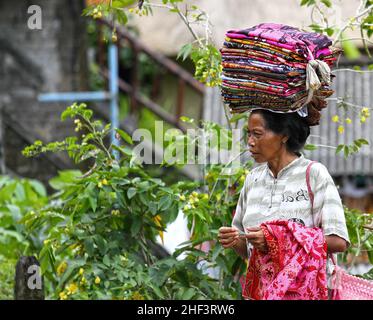 Frauen, die Sarongs verkaufen, die auf ihren Köpfen gebündelt sind, werden in Tegalallang in Ubud, Bali, Indonesien, verkauft Stockfoto