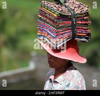 Frauen, die Sarongs verkaufen, die auf ihren Köpfen gebündelt sind, werden in Tegalallang in Ubud, Bali, Indonesien, verkauft Stockfoto