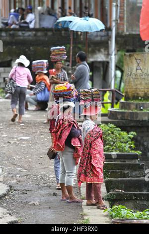 Frauen, die Sarongs verkaufen, die auf ihren Köpfen gebündelt sind, werden in Tegalallang in Ubud, Bali, Indonesien, verkauft Stockfoto