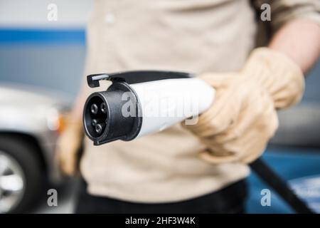 Elektrofahrzeug Smart Charger Plug in Herren Hand Nahaufnahme Foto. Thema „Elektroautos Laden“. Stockfoto