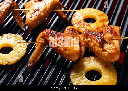 Leckere Hähnchenflügel-Spieße mit Ananasscheiben auf dem Grill Stockfoto