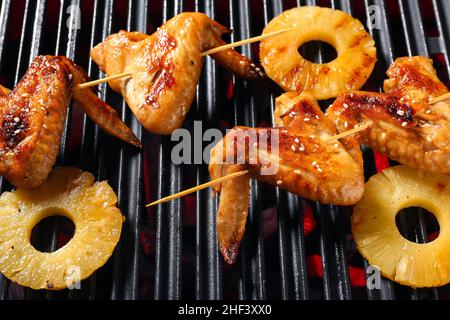 Leckere Hähnchenflügel-Spieße mit Ananasscheiben auf dem Grill Stockfoto