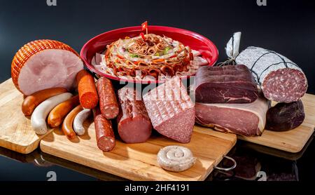 Eine Auswahl an Delikatessenfleisch, darunter Honig gebackener Schinken, parmaschinken, Salamis, gereiftem Rindfleisch und Würstchen auf Holzbrettern Stockfoto