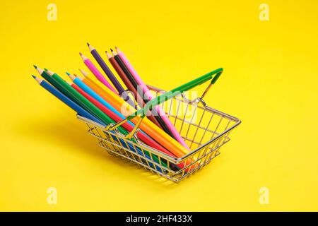 Buntstifte im Warenkorb auf gelbem Hintergrund.Schulbedarf zum Zeichnen Stockfoto