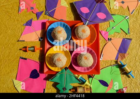 Til laddu oder Sesam ladoo makarsankranti Thema spezielle sankranti traditionelle Süßigkeiten mit bunten Drachen Hintergrund Grußwünsche Stockfoto