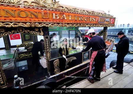 Makrelenfisch, gegrillt für die berühmten Fisch-Sandwiches, serviert von bunten Booten an der Galata-Brücke in Istanbul, Türkei. Stockfoto