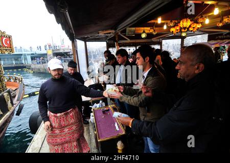 Makrelenfisch, gegrillt für die berühmten Fisch-Sandwiches, serviert von bunten Booten an der Galata-Brücke in Istanbul, Türkei. Stockfoto