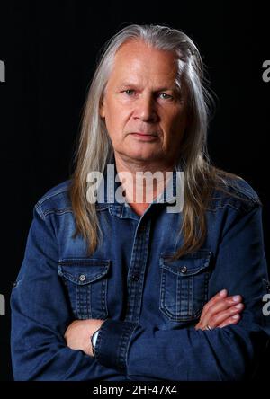 Porträt eines älteren Mannes mit langen grauen Haaren im Studio auf schwarzem Hintergrund Stockfoto