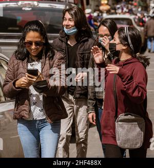 cuenca, Ecuador, 24. Dez 2021 - Freundinnen in COVID-Masken lachen beim Schreiben in der traditionellen Pase del Nino Weihnachts-Parade. Stockfoto