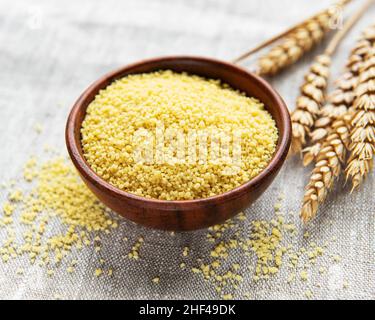 Roher Couscous in einer Holzschale auf dem Tisch Stockfoto