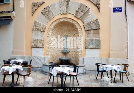 Tische des Restaurants im Freien auf dem Platz vor dem Brunnen in der Altstadt von Bastia, Korsika, Frankreich. Stockfoto