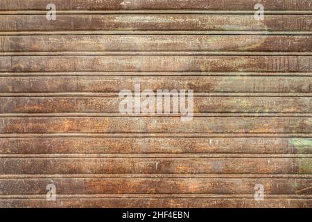 Metallverschluss mit abblätternder Farbe. Vorderansicht des Rollladens verrostet, durch die Elemente verschlechtert. Ideal für Hintergrund, Tapete. Stockfoto