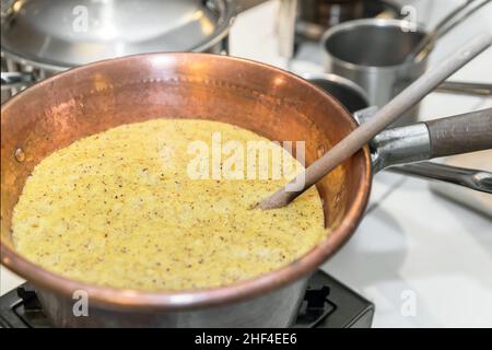 Polenta. Typisches Gericht aus Bergamo, gekocht im traditionellen Kupfertopf. Stockfoto