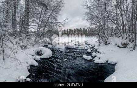 Fließender Fluss in verschneiten Winterlandschaften in Finnland Stockfoto