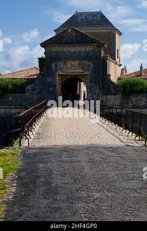 porte des campani in Saint-Martin-de-Ré auf der Ile de Ré an einem sonnigen Tag im Sommer mit Menschen, die auf einem Fahrrad darunter reiten. Stockfoto