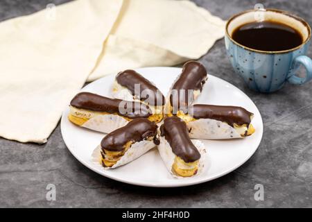 Leckere Ecolirs und eine Tasse Kaffee auf einem dunklen Tisch. Traditionelles französisches Dessert. Gebäck. Nahaufnahme Stockfoto