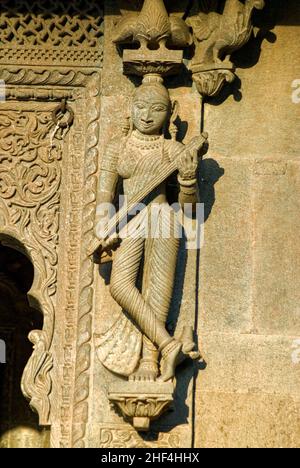 Frau spielt ein in Stein gemeißeltes Veena-Musikinstrument an der Wand des Maheshwar-Tempels Stockfoto