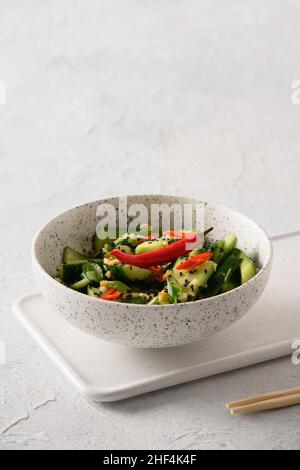 Asiatisch würziger Salat gebrochene Gurken mit frischem Koriander, Ingwer auf weißem Hintergrund. Beliebte chinesische kalte Vorspeise. Nahaufnahme. Vertikales Format. Kopie en Stockfoto