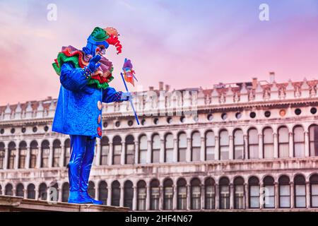 Mann posiert in farbenfrohem harlekin-Kostüm auf dem Markusplatz, Carnevale Di Venezia, Karneval in Venedig, Italien Stockfoto