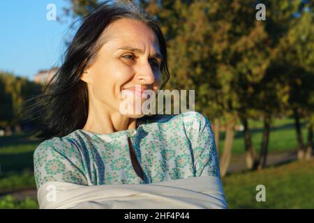 Profil Seitenansicht Porträt einer attraktiven, fröhlichen, verträumten, grauhaarigen Frau mittleren Alters, die sich an sonnigen Tagen im Freien entspannt Stockfoto
