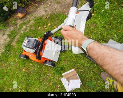 Paris, Frankreich – 12. Juni 2021: POV-Griff am Steuer des neuen Stihl-Rasenmähers und des Auspackens des Steckers Stockfoto