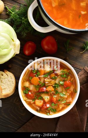 Kohlsuppe in einer Schüssel auf Holzboden. Draufsicht, flach liegend Stockfoto