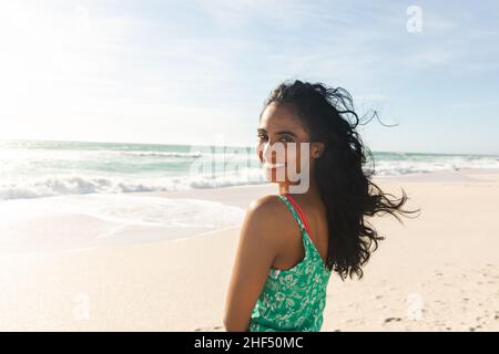 Porträt einer glücklichen, schönen jungen Birazialfrau, die über die Schulter auf den Strand blickt und einen sonnigen Tag genießt Stockfoto