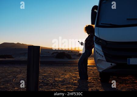 Frau in Silhouette gegen Sonnenuntergang schönes Licht. Reisen Sie Menschen mit Camper Camping Auto van für Sommerurlaub oder Freiheit Lebensstil. Personen, die p Stockfoto