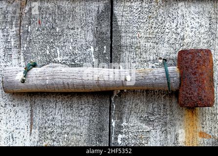 Alter rostiger Hummer auf Holzverwitterungstisch - Vintage kleiner rostiger Hammerkopf auf Holztisch Stockfoto