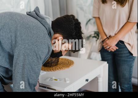 Junger Mann überprüft das Ergebnis des Coronavirus-Tests zu Hause Stockfoto