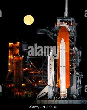 Ein fast voller Mond geht unter, als das Space Shuttle Discovery auf der Startfläche 39A im Kennedy Space Center in Cape Canaveral, Florida, 11. März 2009 sitzt Stockfoto