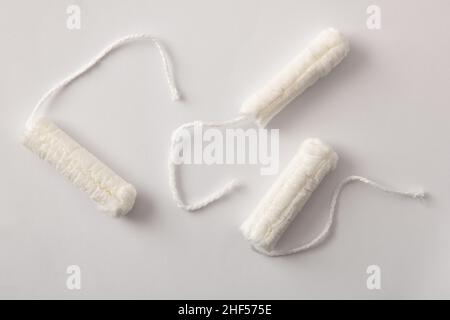 Drei weiche, schützende und saugfähige Tampons aus Baumwolle für die Damenpflege auf weißem Hintergrund. Draufsicht. Horizontale Zusammensetzung. Stockfoto