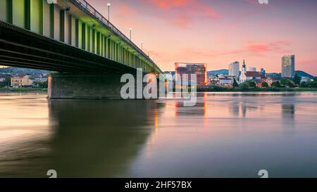 Linz, Österreich. Stadtbild des Flussufers Linz, Österreich bei Sonnenuntergang im Sommer mit Spiegelung der Lichter der Stadt in der Donau. Stockfoto