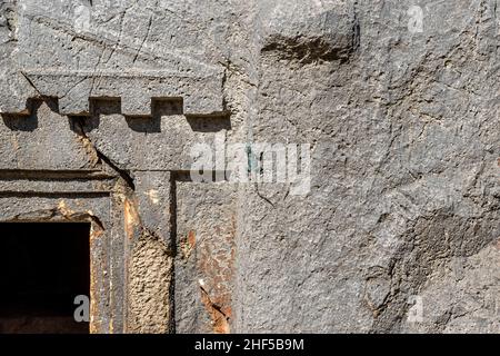 Blaue Eidechse, die sich in der Sonne sonnen, sitzt an der Wand eines alten Steingrabes in Myra Stockfoto