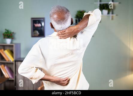 Rückansicht eines kranken alten Mannes, der sich durch das Halten des Halses und des Rückens dehnt spanien - Konzept des Leidens an Osteoarthritis, spanien-Verletzungen und Gelenkschmerzen durch Stockfoto