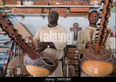 SENEGAL, Benediktinerkloster Keur Moussa, Mönche arbeiten in Werkstatt, um die afrikanische Kora-Brückenharfe zu bauen, spielen eine neu gebaute Kora / Senegal, Benediktinerkloster Keur Moussa, Musikinstrumentbau Werkstatt, Bau der Kora ein traditionelles westafrikanisches Saiteninstrument, Mönch spielen neue fertiggestellte Kora Stockfoto