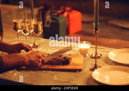 Selektiver Schwerpunkt der weiblichen Schneiden köstliche frisch gebackene hausgemachte xms-Kuchen mit Messer, feiern Heiligabend oder Neujahr mit Freunden oder Familie Stockfoto