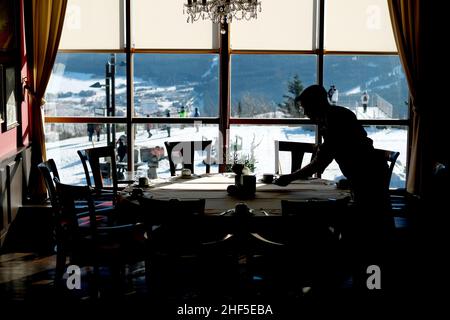 Oberwiesenthal, Deutschland. 14th Januar 2022. Ein Mitarbeiter in einem Hotel am Fichtelberg stellt einen Tisch. Nach der koronabedingten Pause öffnen sich die Skigebiete unter hygienischen Bedingungen. Quelle: Sebastian Willnow/dpa-Zentralbild/dpa/Alamy Live News Stockfoto