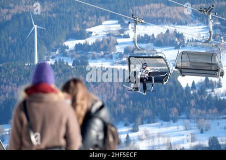 Oberwiesenthal, Deutschland. 14th Januar 2022. Ein Wintersportler sitzt in der Gondel eines Lifts auf dem Fichtelberg. Nach der koronabedingten Pause öffnen sich die Skigebiete unter hygienischen Bedingungen. Quelle: Sebastian Willnow/dpa-Zentralbild/dpa/Alamy Live News Stockfoto