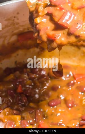 Bohnen mit Gemüse und gelber Sauce in einer Aluminiumpfanne Stockfoto