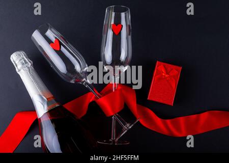 Sektflöten mit rotem Band durch Geschenkbox und Flasche auf grauem Hintergrund gebunden, Kopierraum Stockfoto