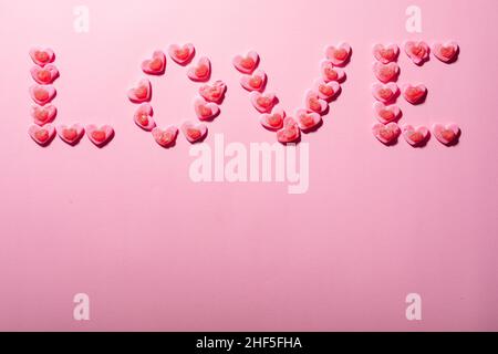 Liebessext aus herzförmigen Bonbons auf rosa Hintergrund, Copy Space Stockfoto
