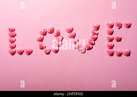 Liebessext aus herzförmigen Bonbons auf rosa Hintergrund isoliert, Copy Space Stockfoto
