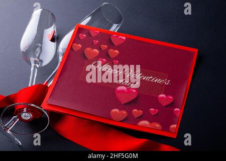 Geschenkkarte mit glücklichen Valentinstag Text von Sektflöten mit rotem Band eingewickelt Stockfoto
