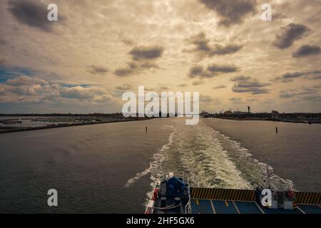 Hafenausfahrt Rostock. Blick zurück nach Warnemünde vom Schiff, das nach Schweden fährt. Wolkiger Himmel im Frühling. Es geht in den Urlaub Stockfoto