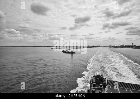 Hafenausfahrt Rostock. Blick zurück nach Warnemünde vom Schiff, das nach Schweden fährt. Wolkiger Himmel im Frühling. Es geht in den Urlaub Stockfoto