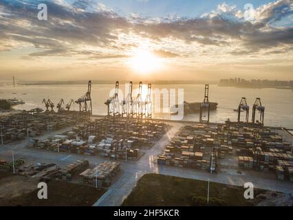 (220114) -- SHANGHAI, 14. Januar 2022 (Xinhua) -- Luftfoto vom 5. Dezember 2021 zeigt die Sonnenaufgangsszenerie des internationalen Containerhafens Yangpu in der Wirtschaftsentwicklungszone Yangpu in der südchinesischen Provinz Hainan. Chinas Außenhandel stieg 2021 erneut an und überstieg erstmals 6 Billionen US-Dollar, obwohl die COVID-19-Pandemie den Welthandel weiterhin belastet, zeigten offizielle Daten am Freitag: Der gesamte Warenhandel belief sich auf 6,05 Billionen US-Dollar, Laut der General Administration of Customs (GAC) sind es gegenüber dem Vorjahr 1,4 Billionen US-Dollar. Die tr Stockfoto