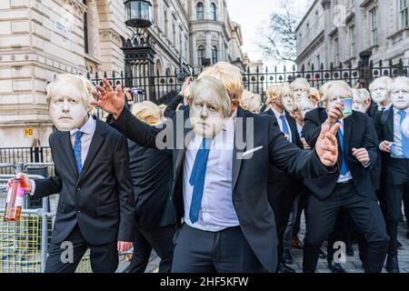 WESTMINSTER, LONDON, GROSSBRITANNIEN. 14th Januar 2022. Eine Gruppe von Boris Johnson-Imitatoren, die blonde Perücken und Masken tragen, inszenieren eine humorvolle Lockdown-Party außerhalb der Downing Street, während sie tanzen und „Boris liebt eine Party“ singen. Premierminister Boris Johnson hat bei den Fragestunde des Premierministers am Mittwoch im Parlament zugegeben, dass er am 20. Mai 2020 an einer Gartenparty in der Downing Street teilgenommen habe, während strikter Beschränkungen durch das Coronavirus und der Vorwürfe, dass Mitarbeiter der Downing Street in der Nacht vor der Königin auf zwei Partys Alkohol getrunken hätten Allein betrübt über Prinz Philipps Fune Stockfoto