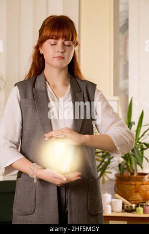 Junge rothaarige Frau, die reiki-Energie in den Händen hält Stockfoto